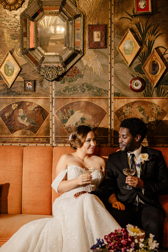 bride and groom cuddle on couch with champagne glasses