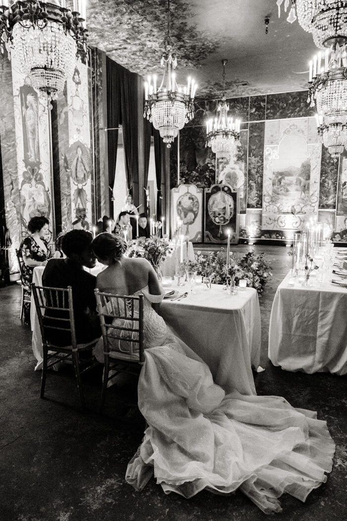 bride and groom lean against each other at wedding reception