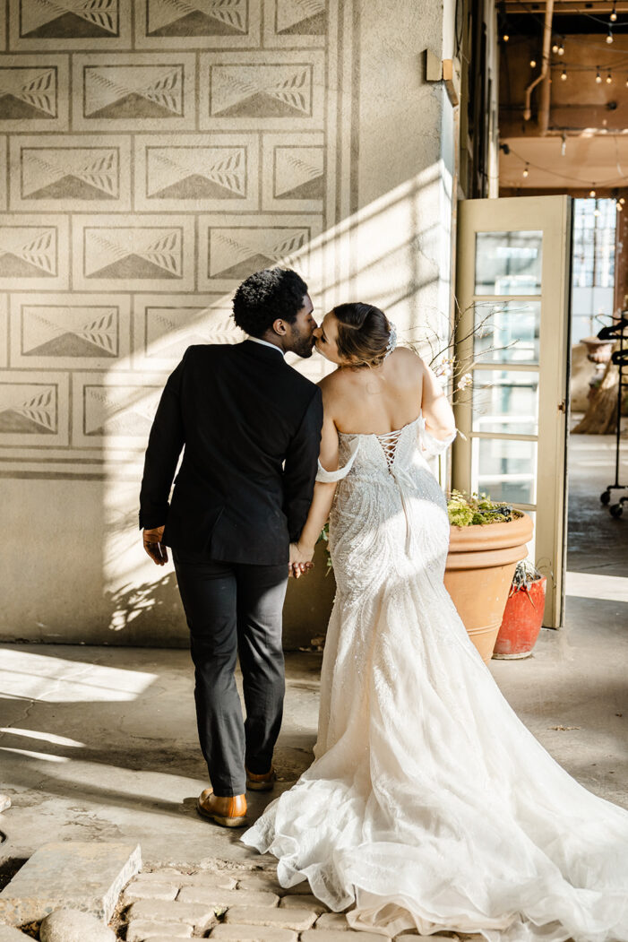 bride and groom walk away and lean in for kiss