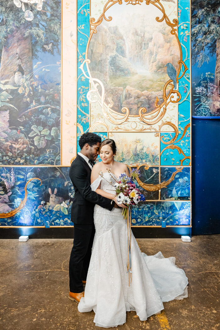 bride and groom stand in a ballroom with painted walls
