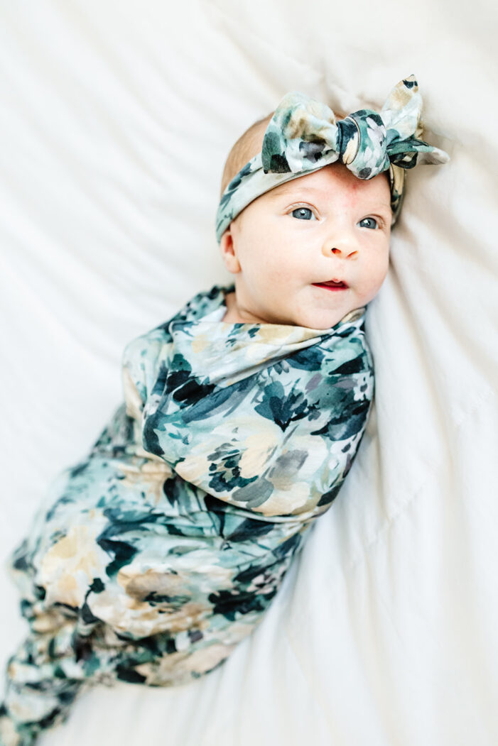baby with blue eyes looks up from bed
