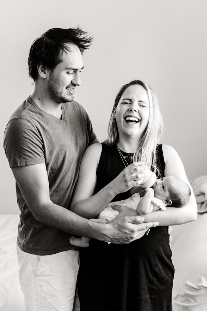 mom and dad snuggle baby and laugh