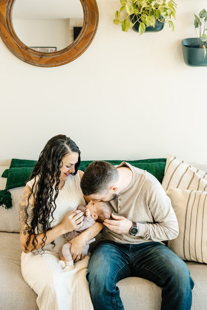 mom dad and baby snuggle together on couch