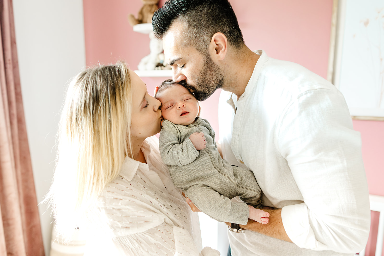 mom and dad kiss newborn