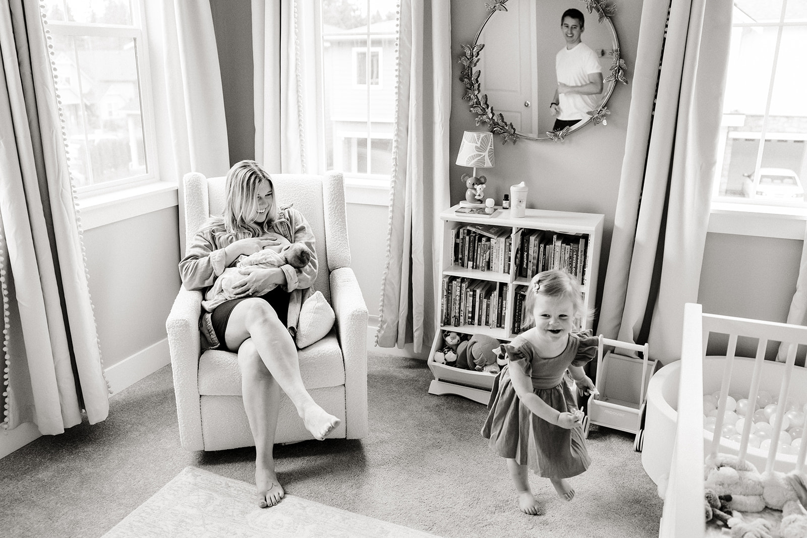 mom feeds baby while toddler runs around