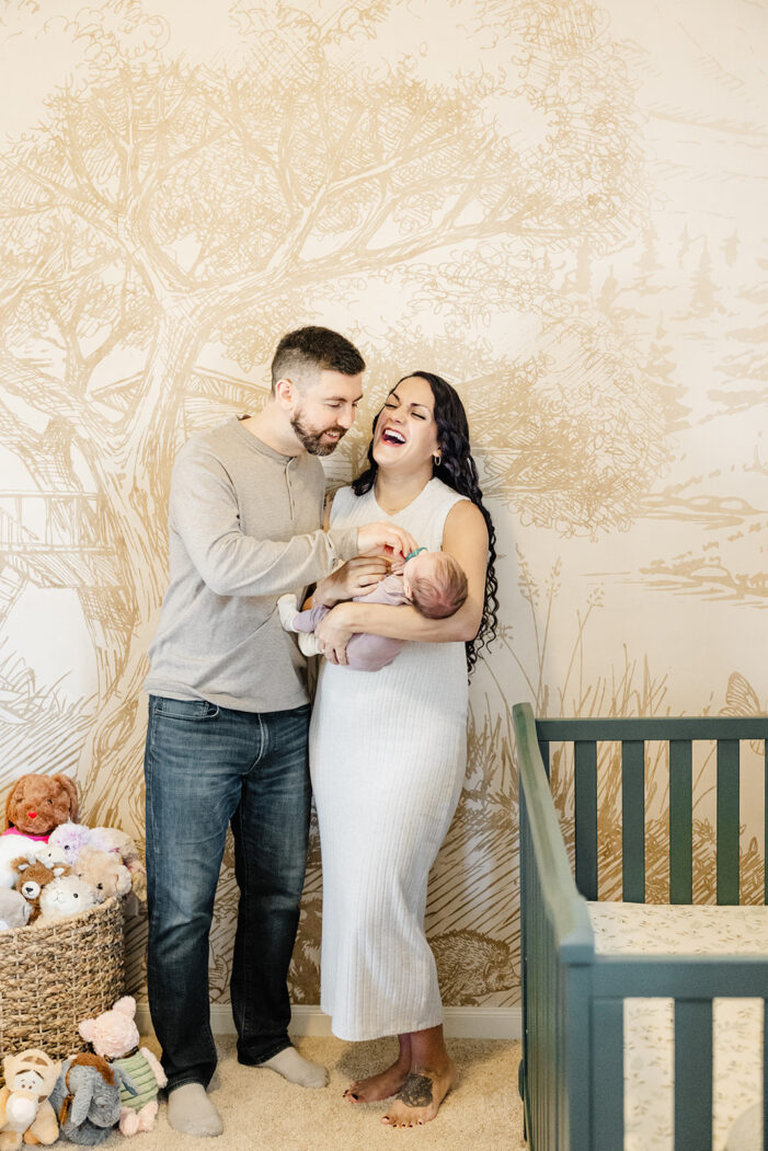 mom laughs and holds baby in nursery