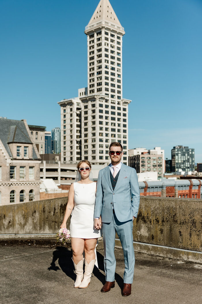 bride and groom stand in front of seattle skyline