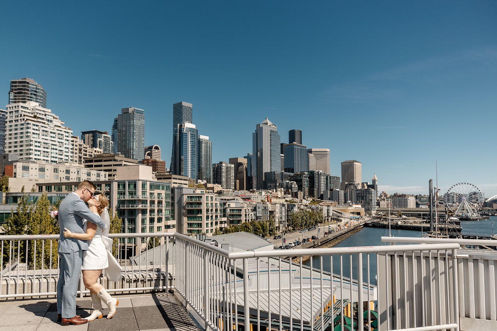 bride and groom stand in front of seattle skyline