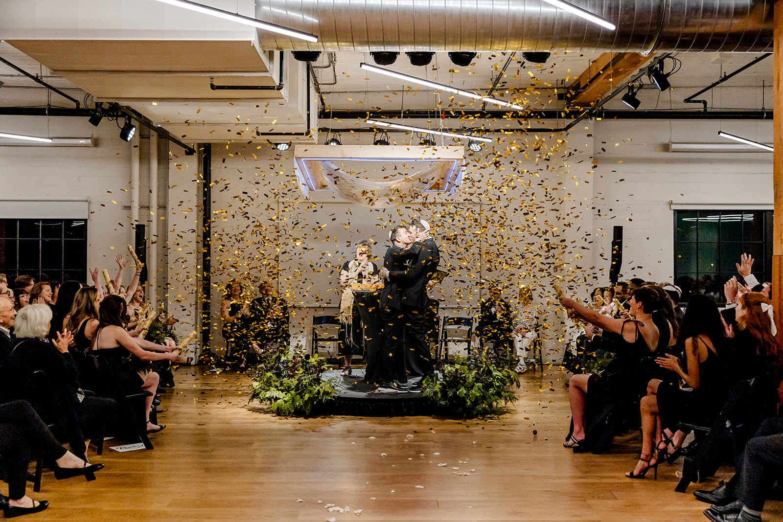 two grooms kiss while confetti drops down on them