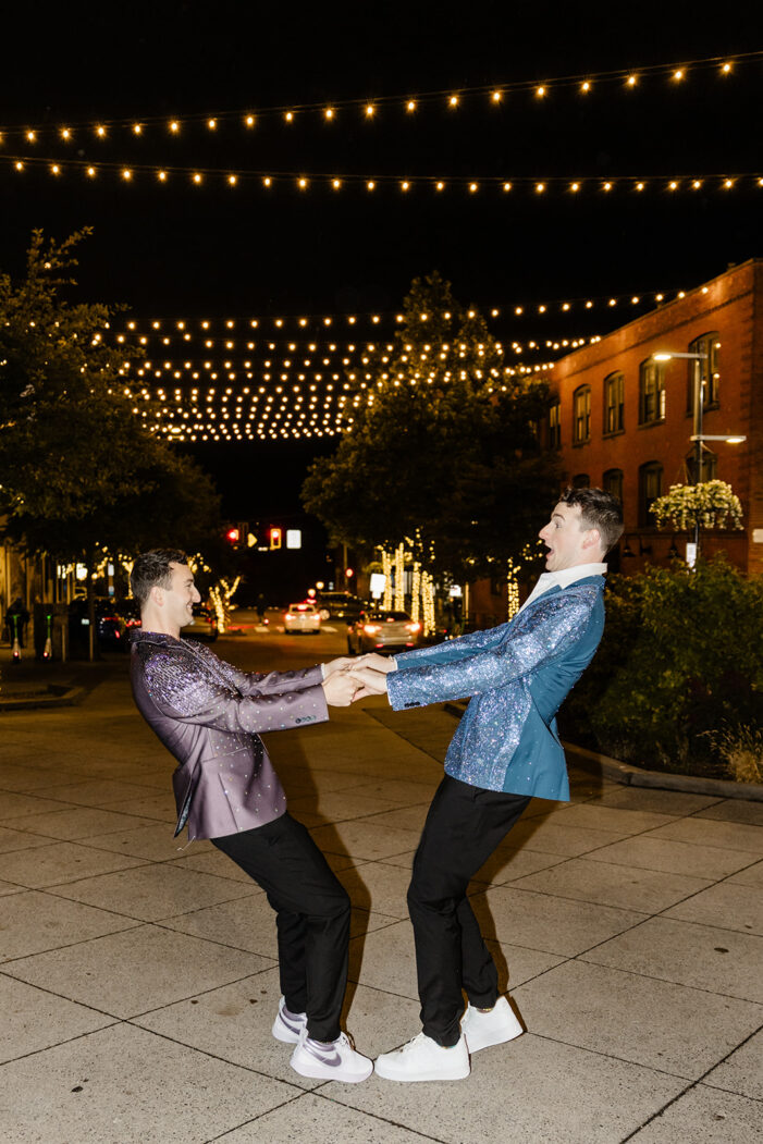 two grooms spin around wearing bright suit jackets