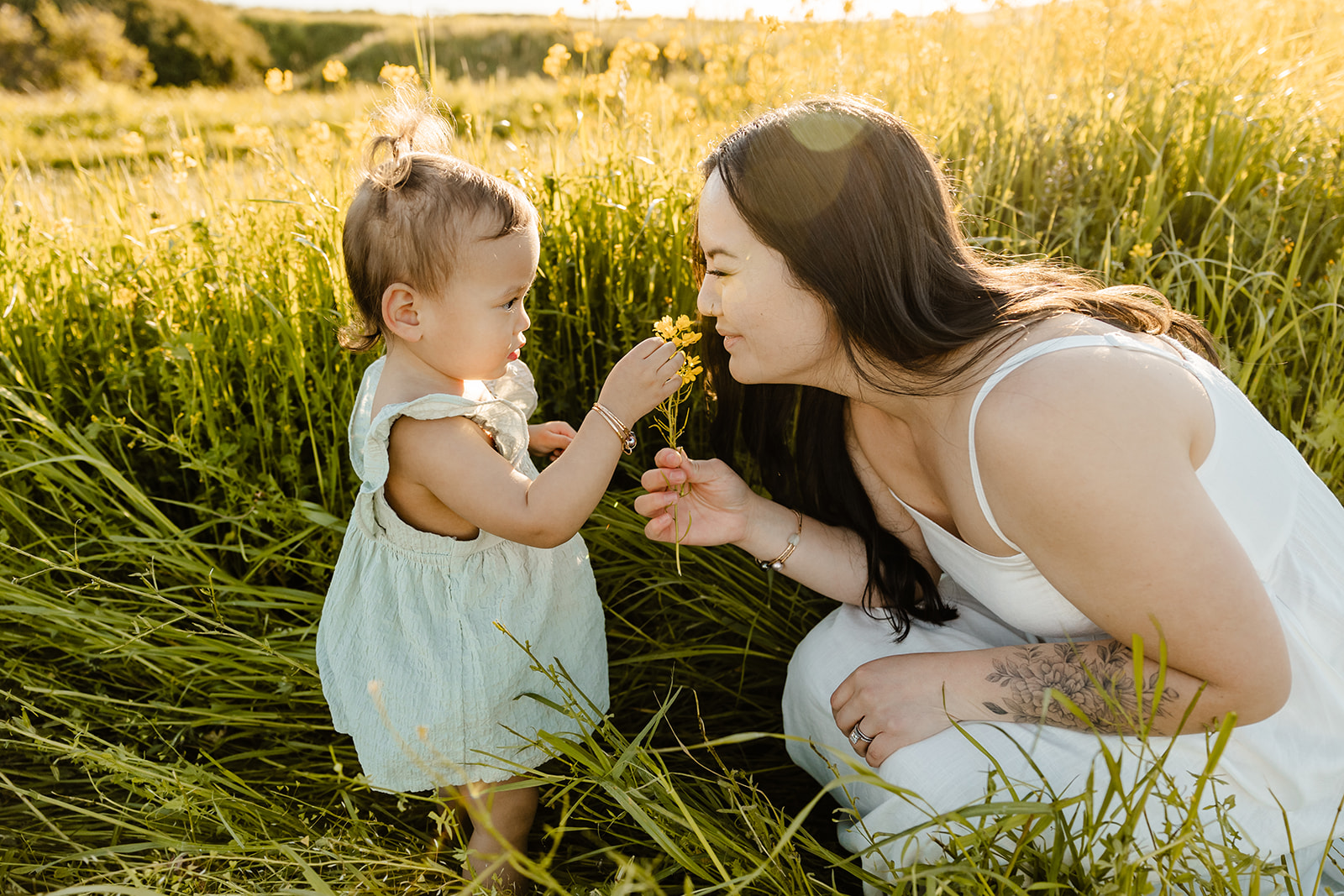 mom smells flower from little girl