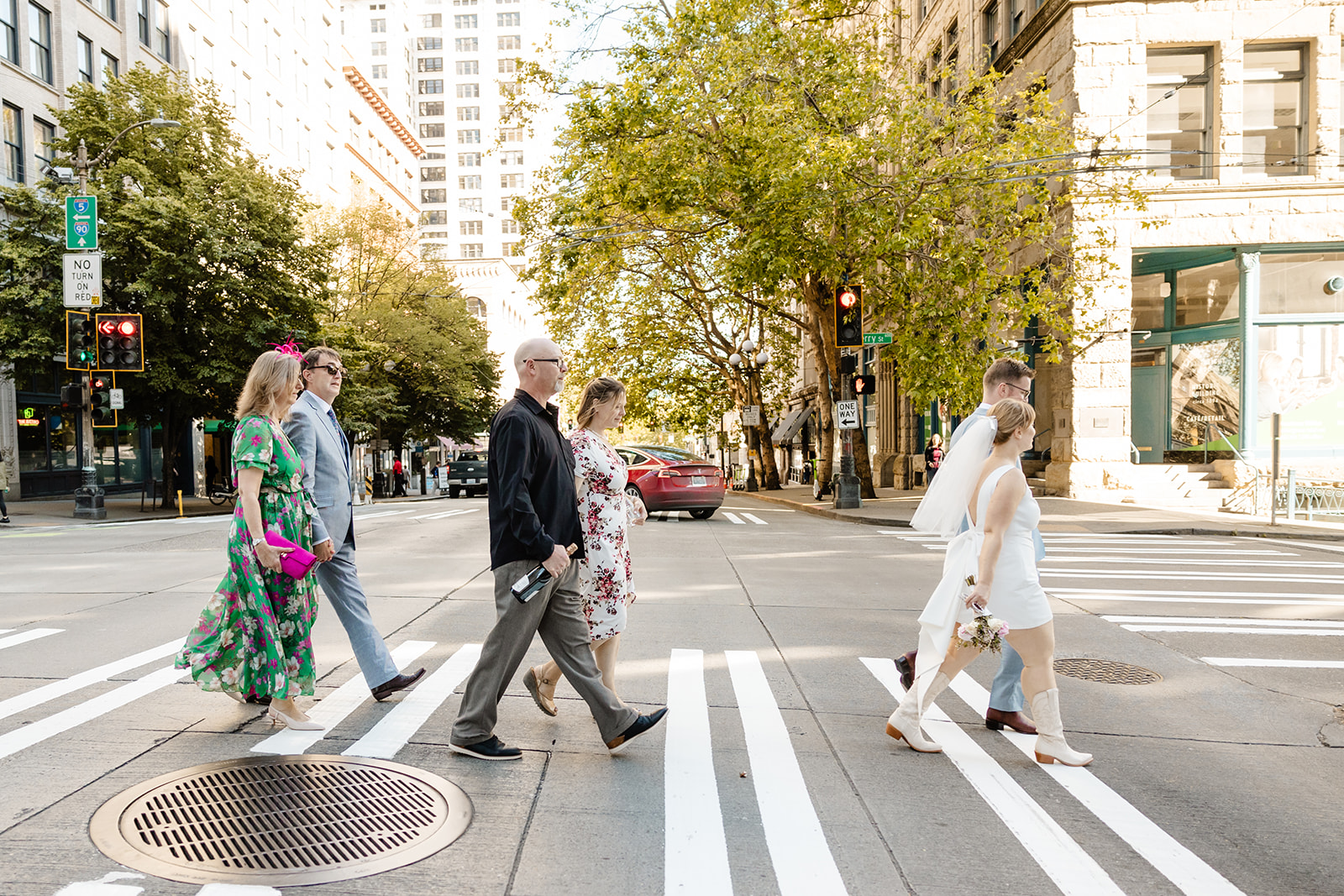 bride and groom walk across street with family