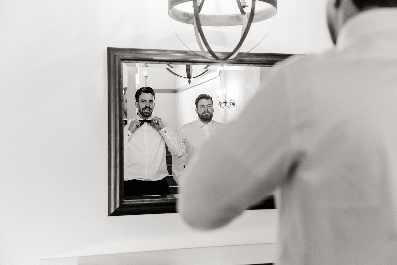 groom straightens tie looking in mirror