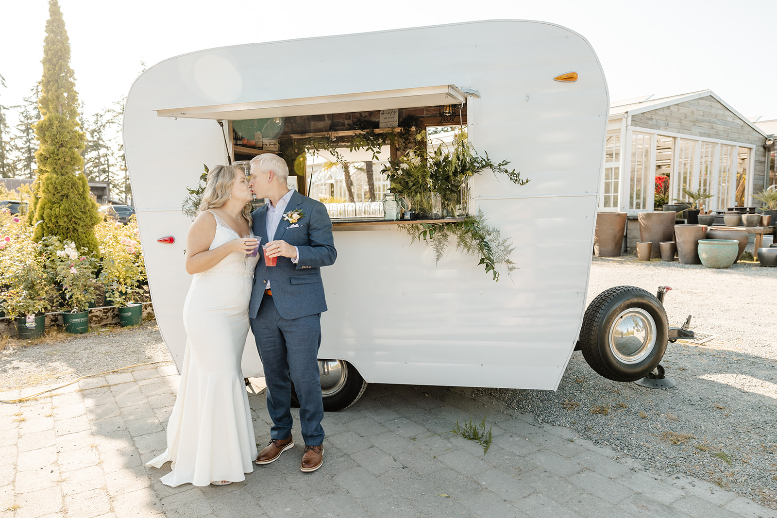 bride and groom kiss in front of bar trailer