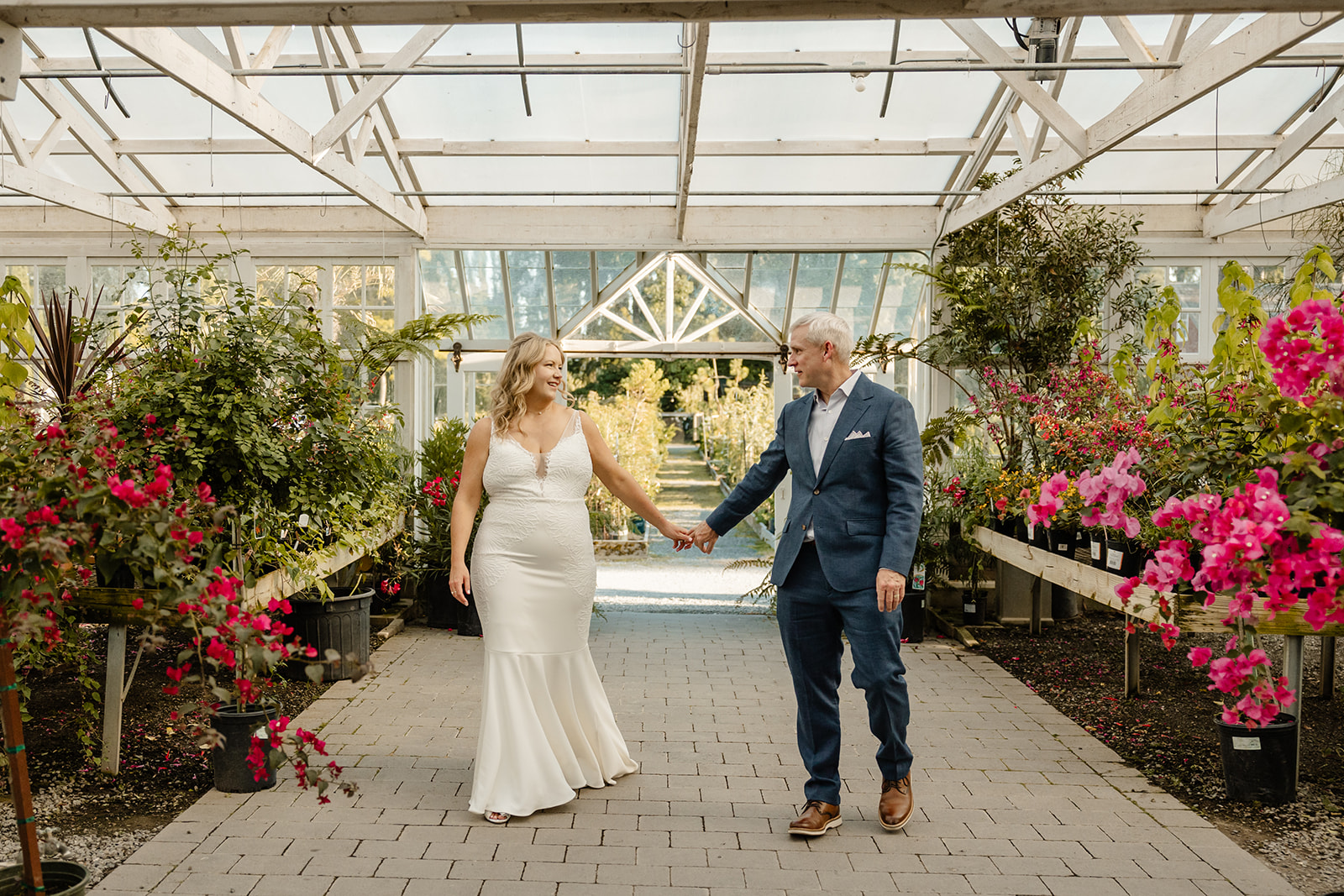 bride and groom walk through green house