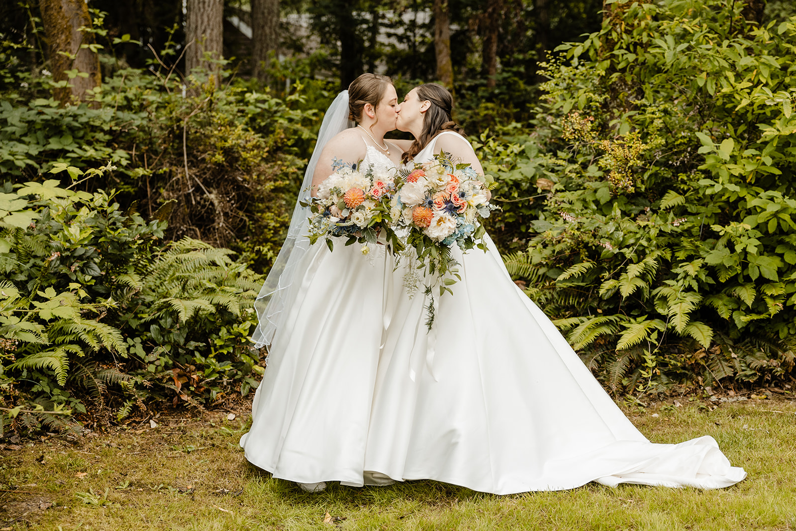 brides kissing in front of forest