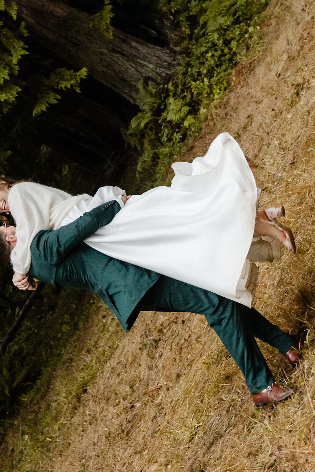 bride and groom stand in front of forest