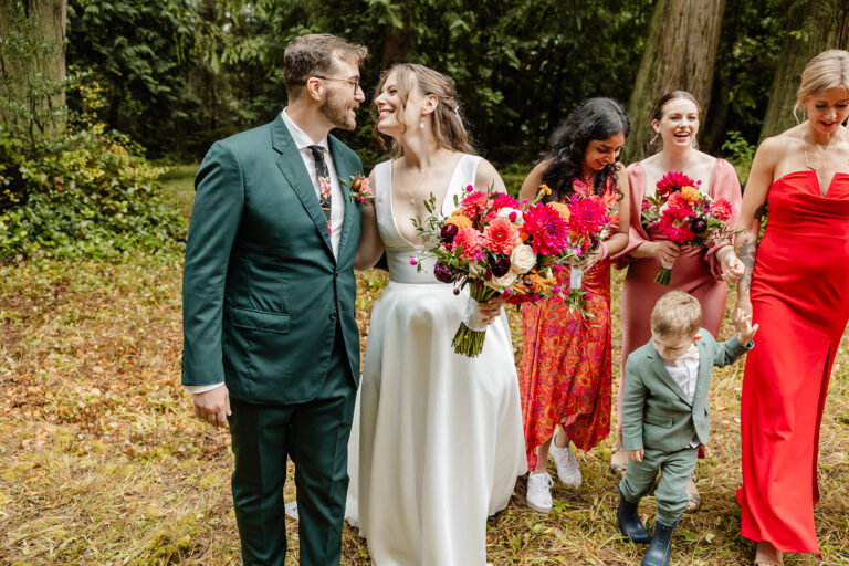 bride and groom almost kiss as bridesmaids in bright colors follow