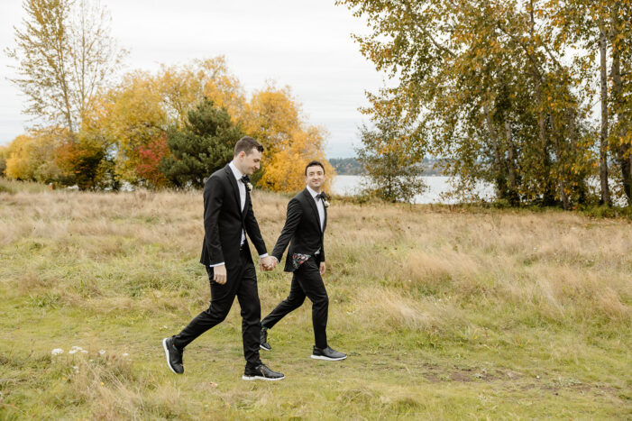 grooms walking together through field