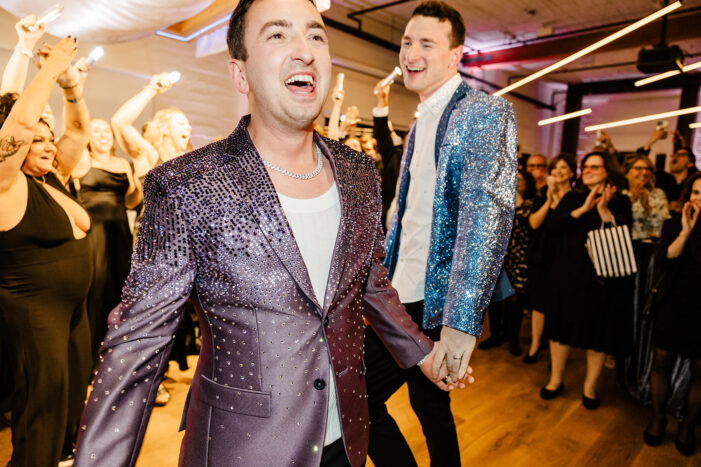 grooms surrounded by love as they enter reception