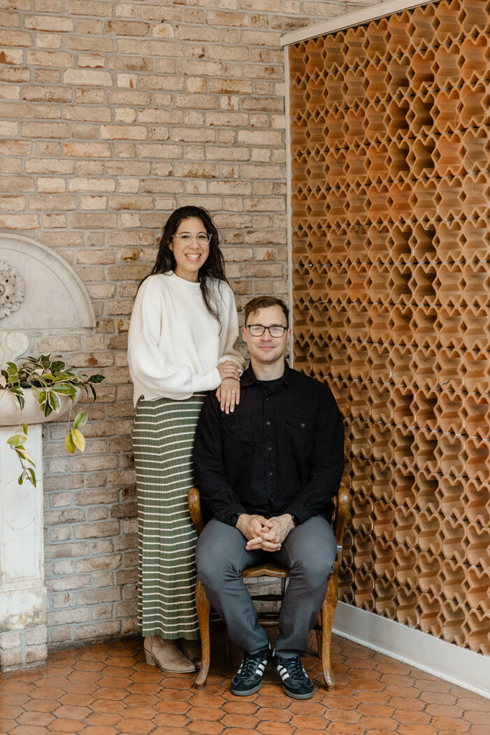 couple sits against a brick wall