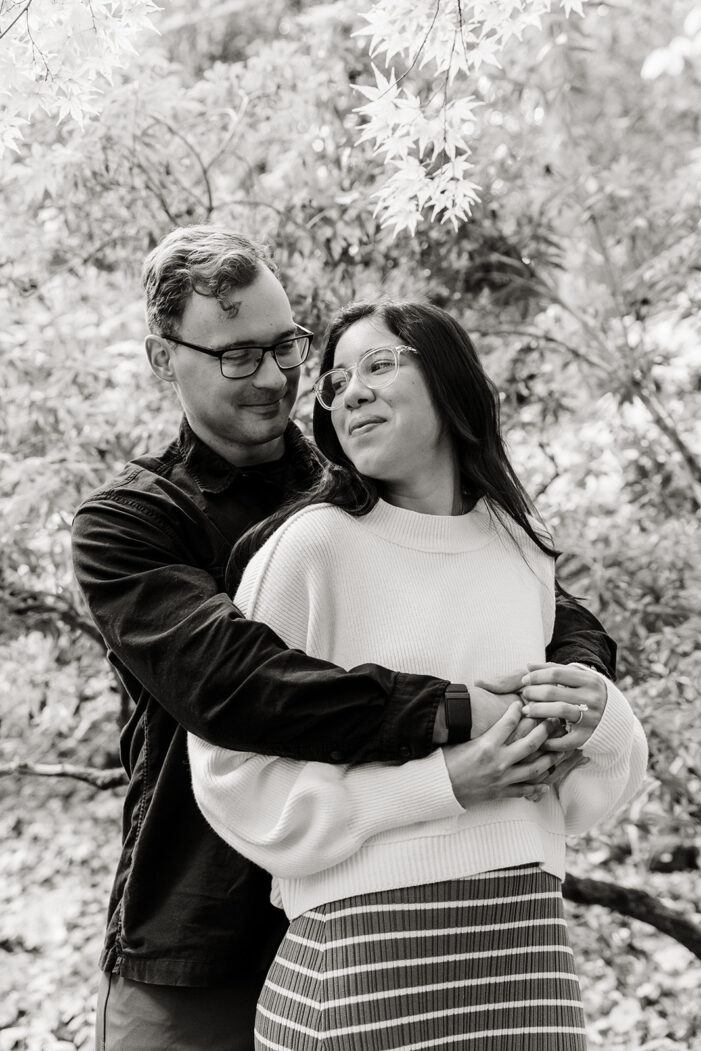 couple cuddles amongst trees