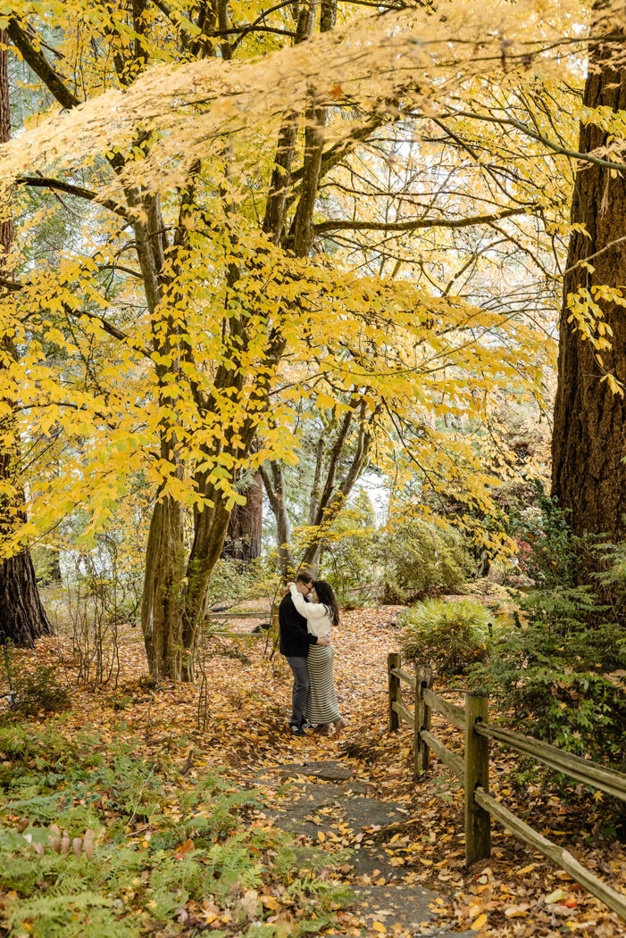couple embraces amongst autumn leaves