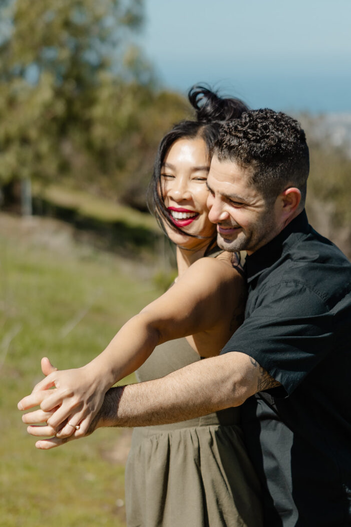man and woman embrace on hillside