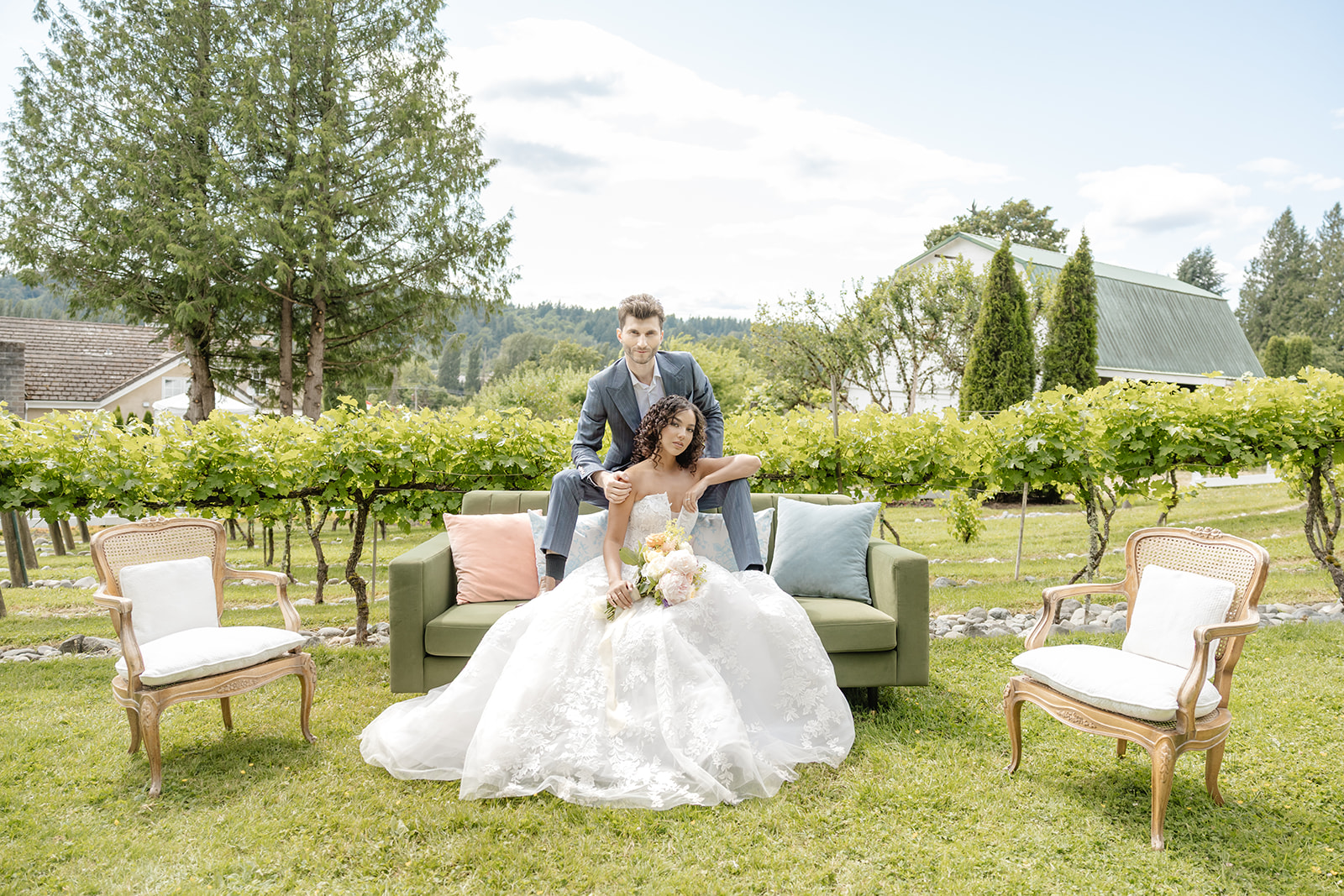 bride and groom on a couch with vineyard around them