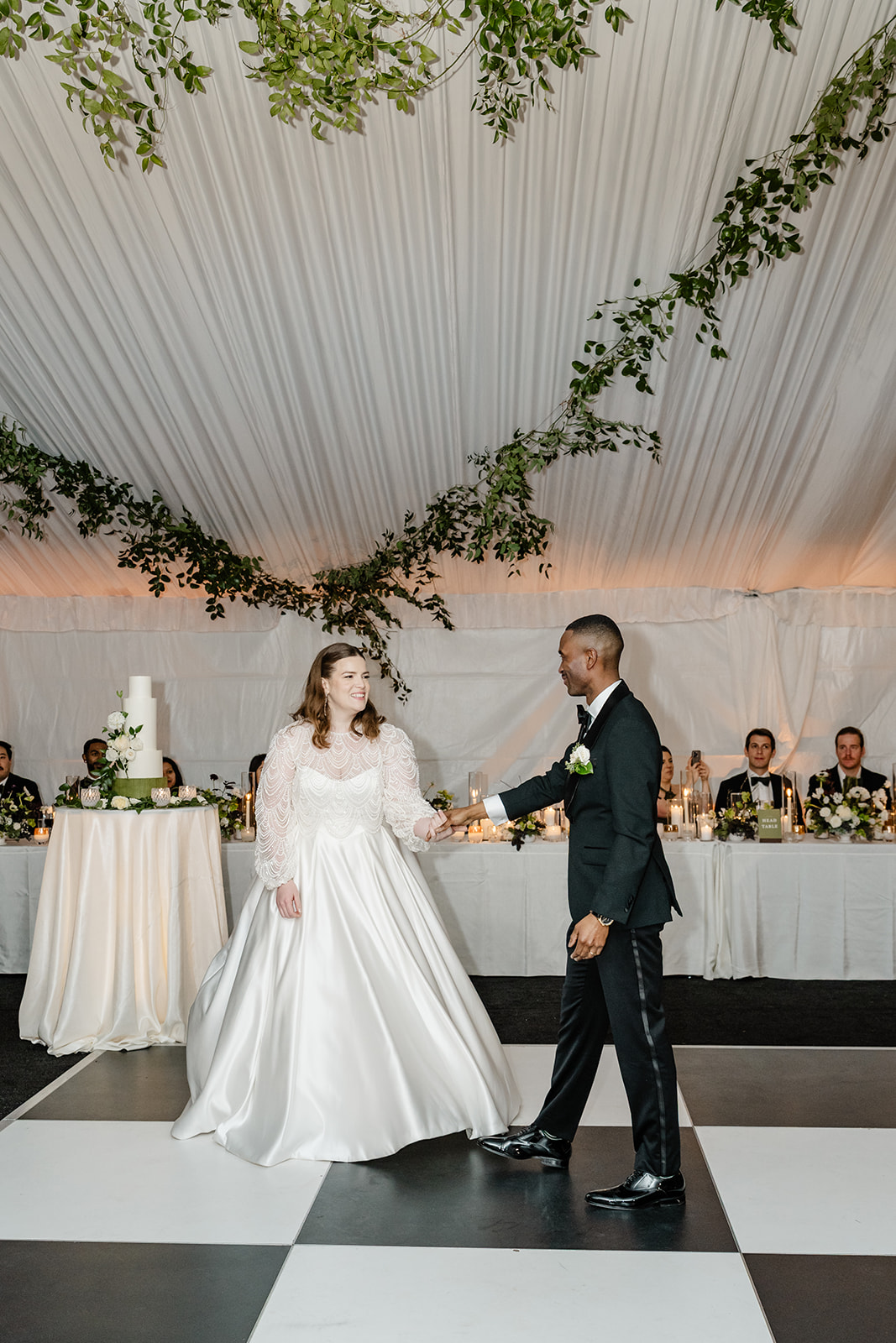 elegant tented reception with greenery and checkered dance floor in seattle washington