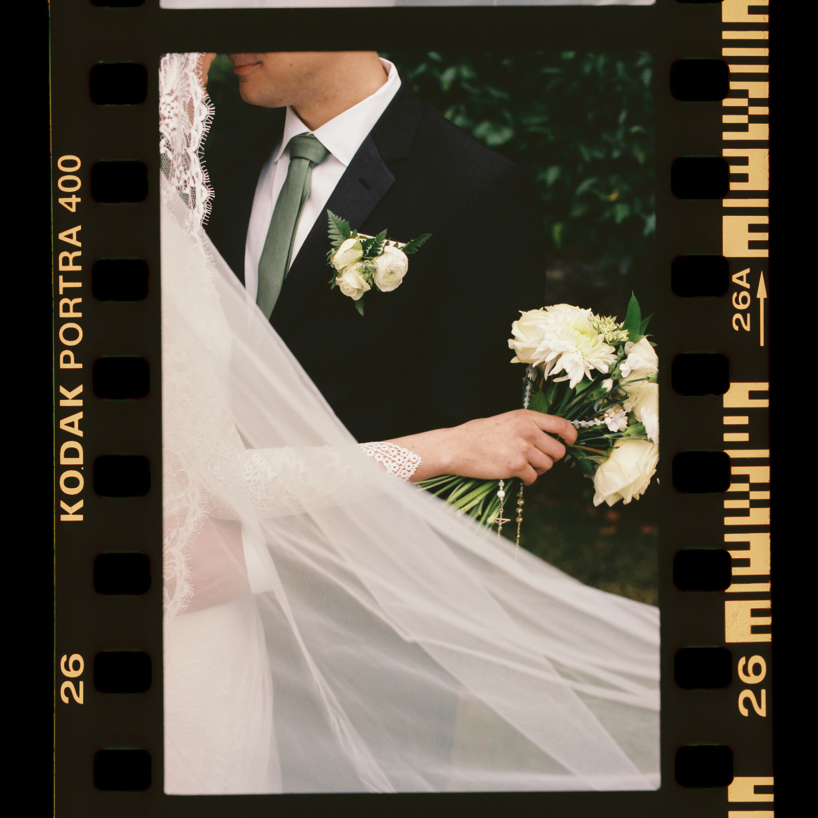 35mm film photographer couple embracing showcasing veil during rainy wedding day photos