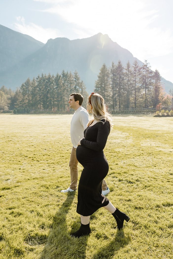 couple walks through field during maternity shoot