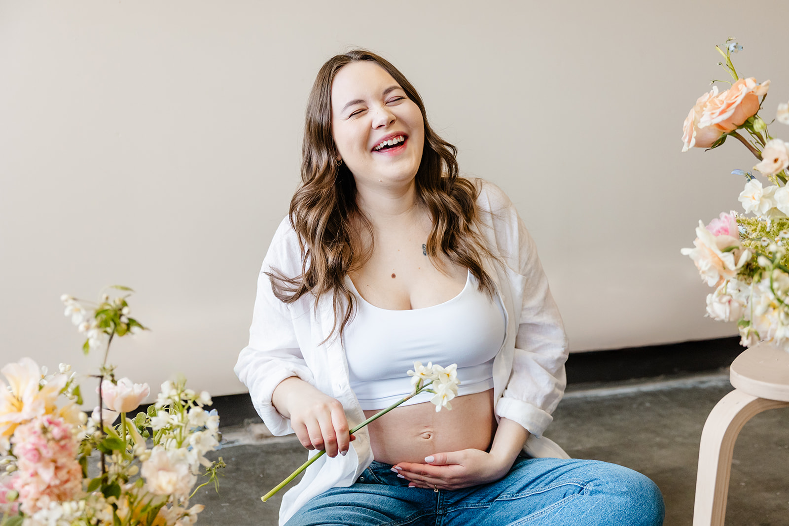 pregnant person sits in studio amongst flowers