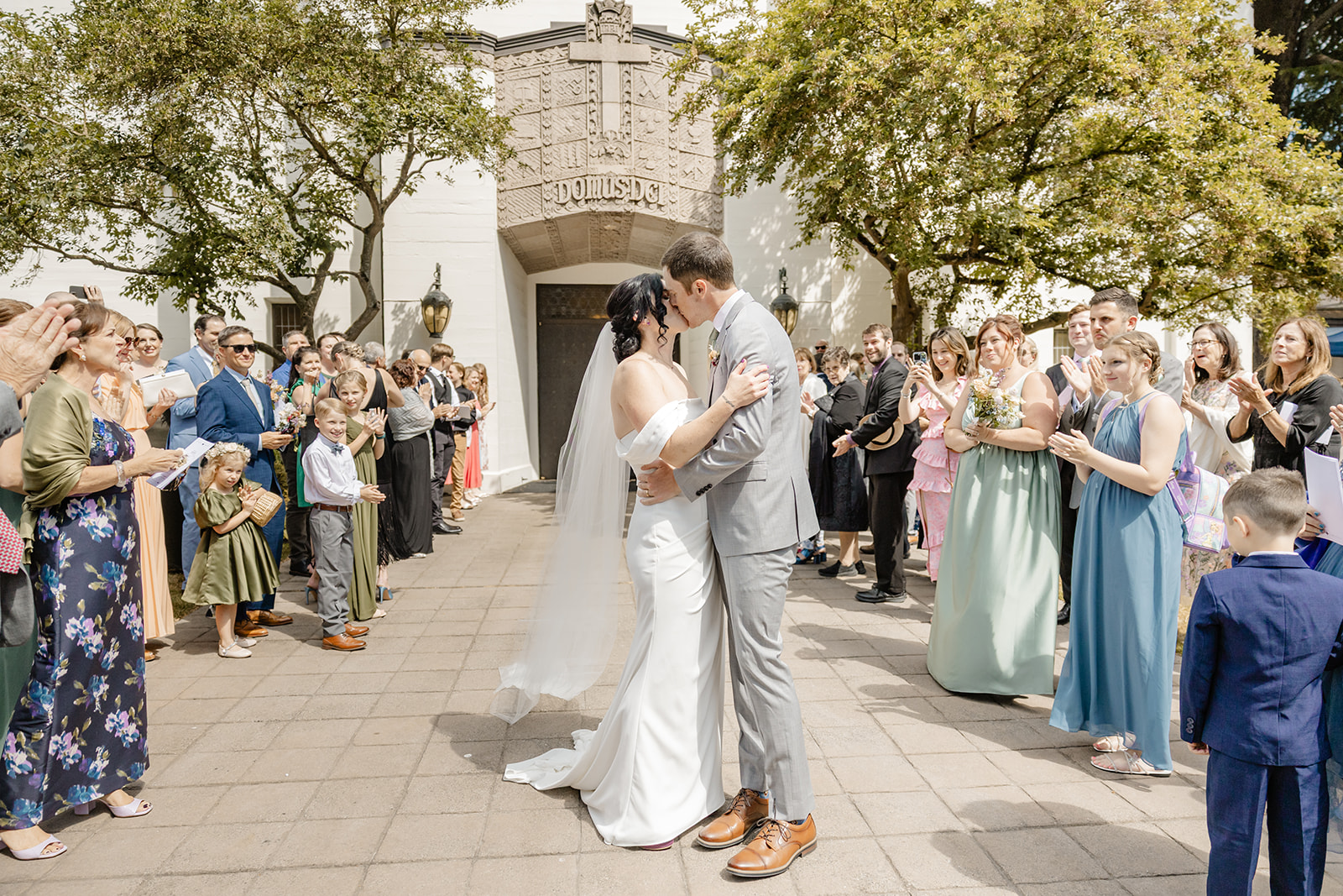 bride and groom kiss with cheers around them