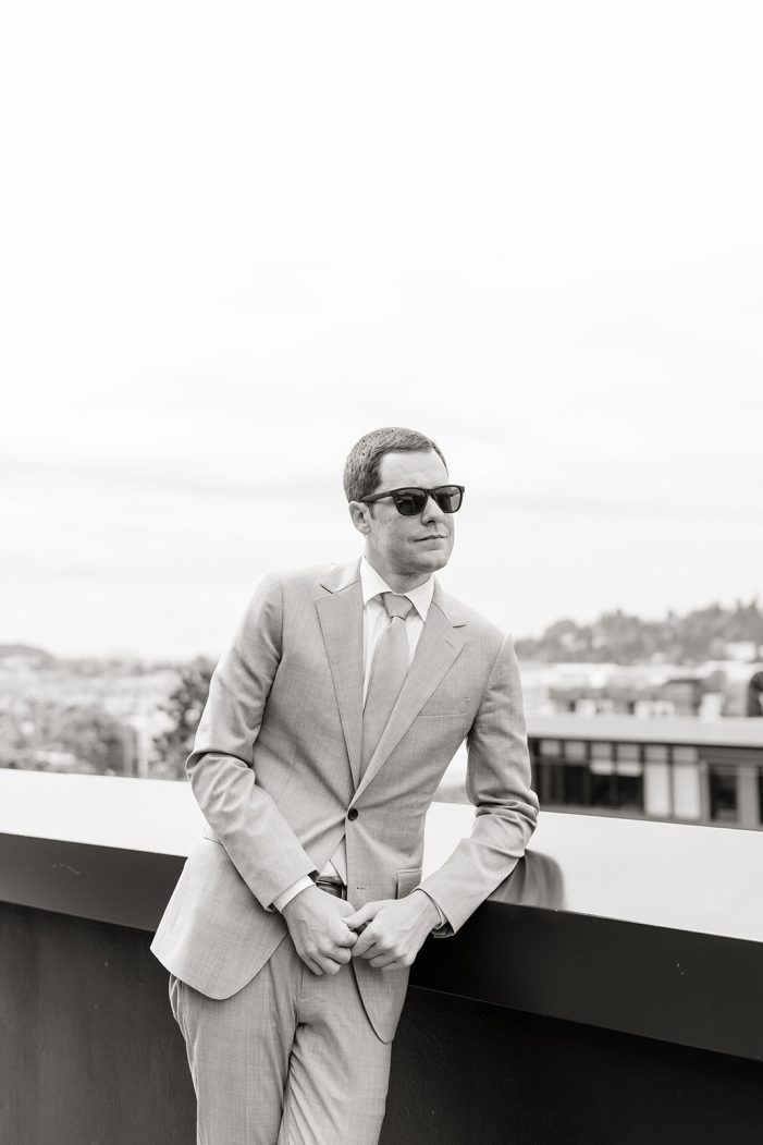 groom in sunglasses leans on banister