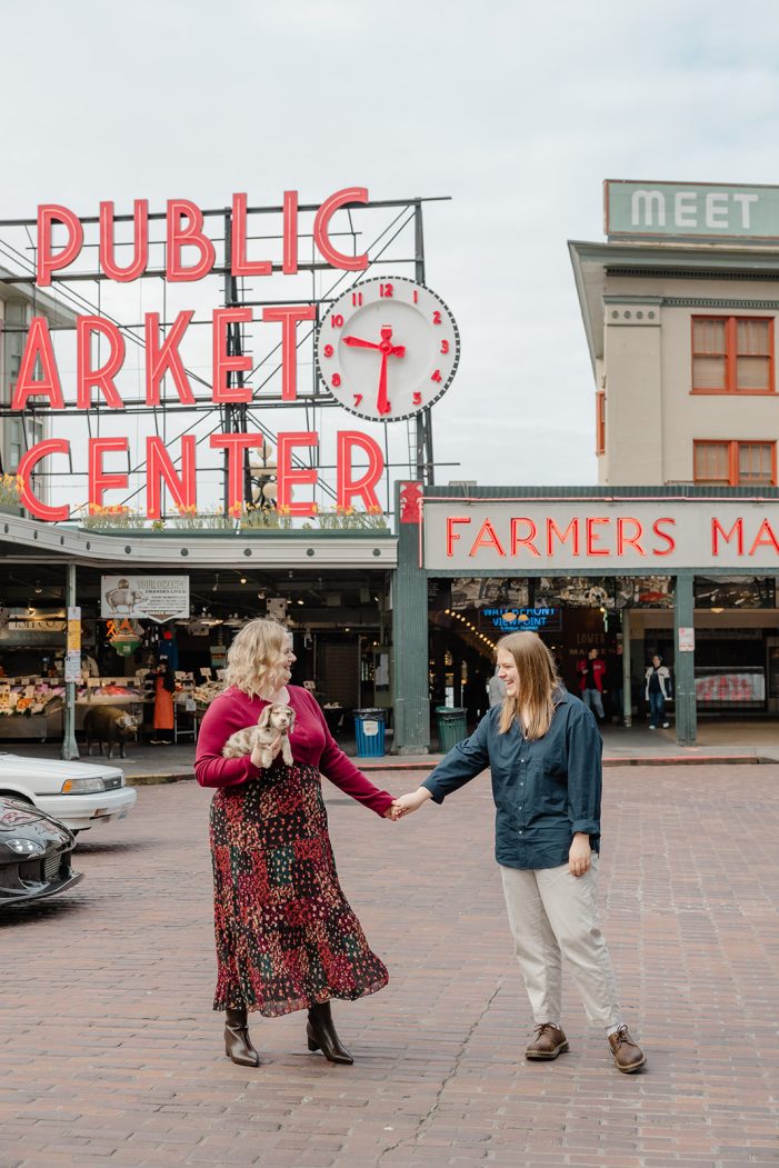 couple walks hand in hand with dog at public market center