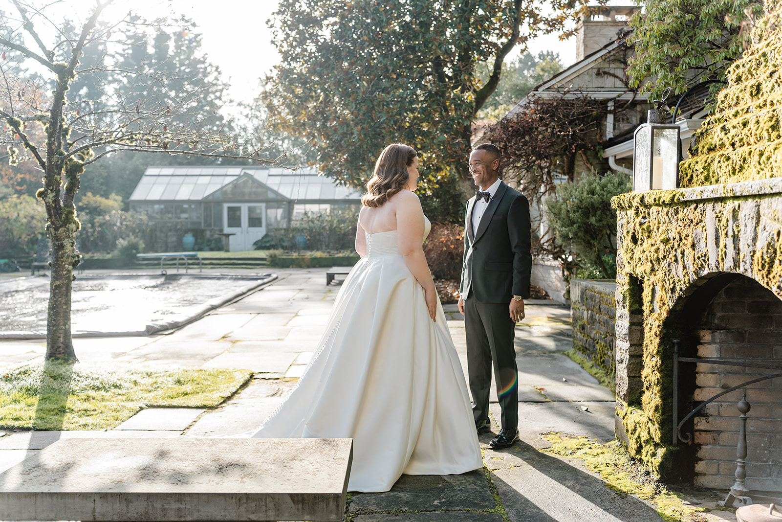 bride and groom stand in front of outdoor fireplace