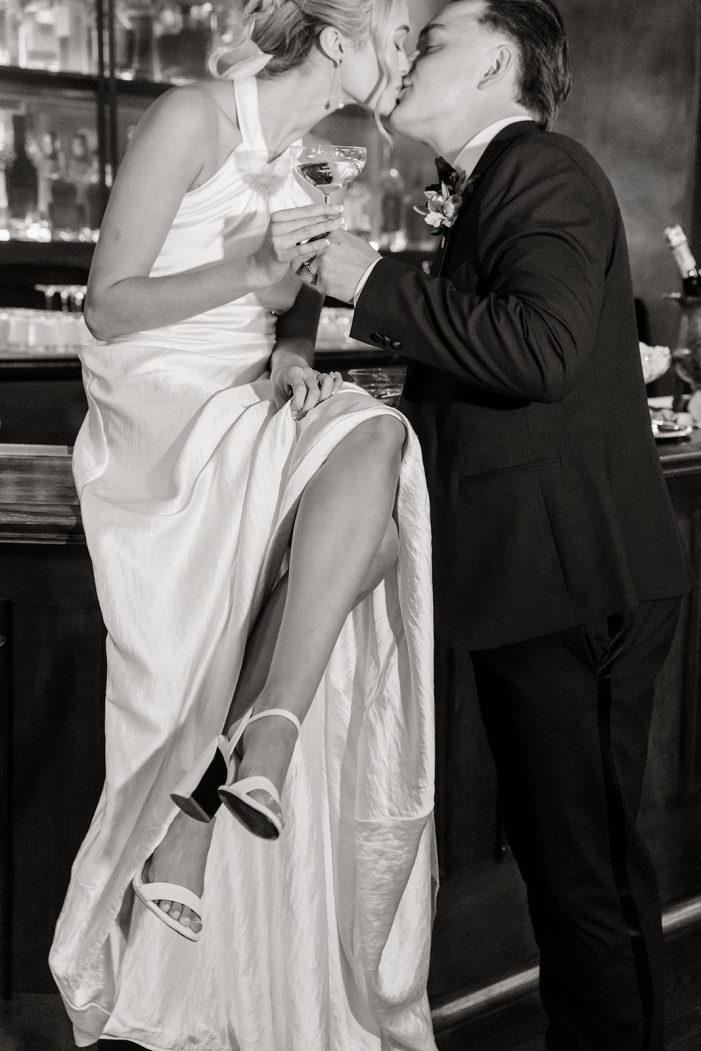 bride and groom kiss on bartop