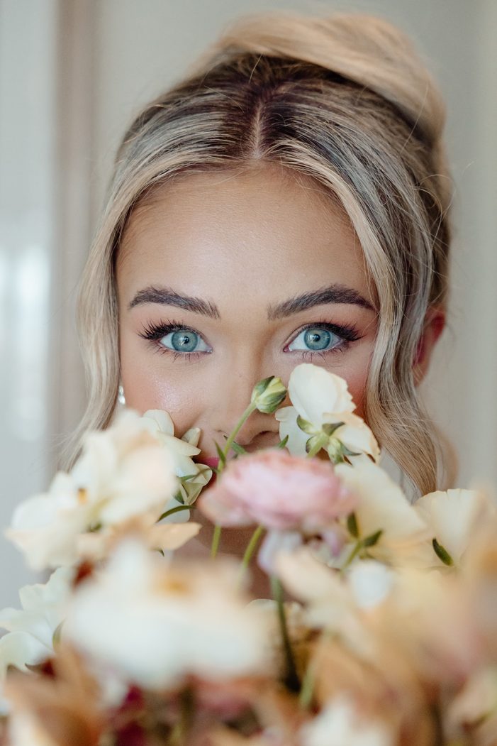 bride peeks over top of flowers