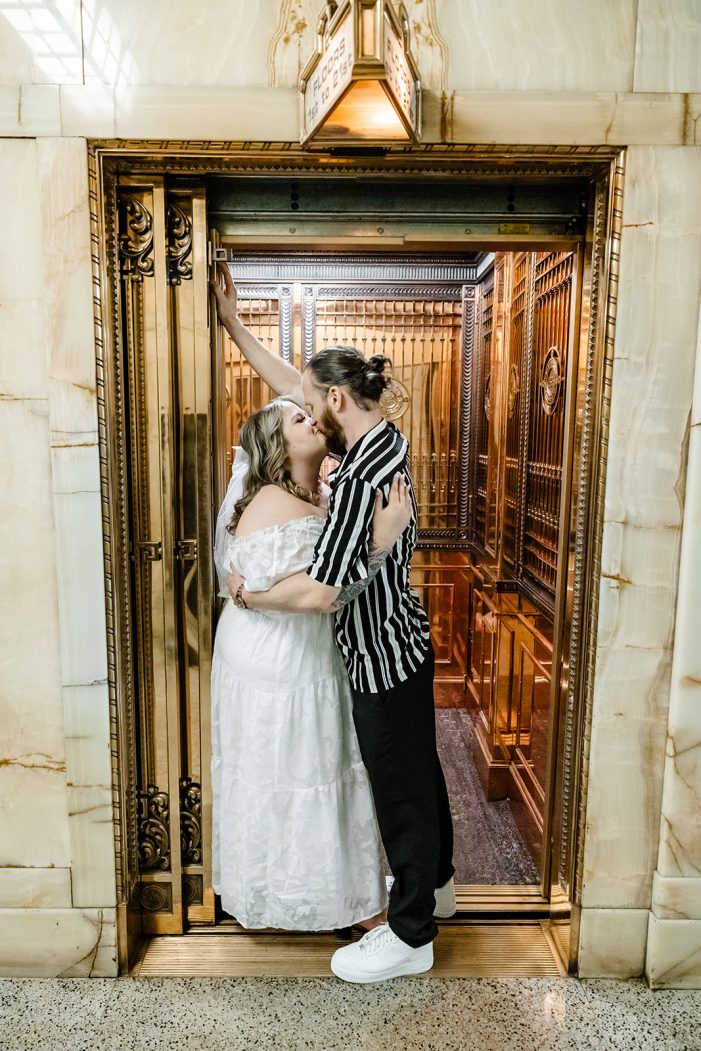 couple kisses in the entrance to an elevator