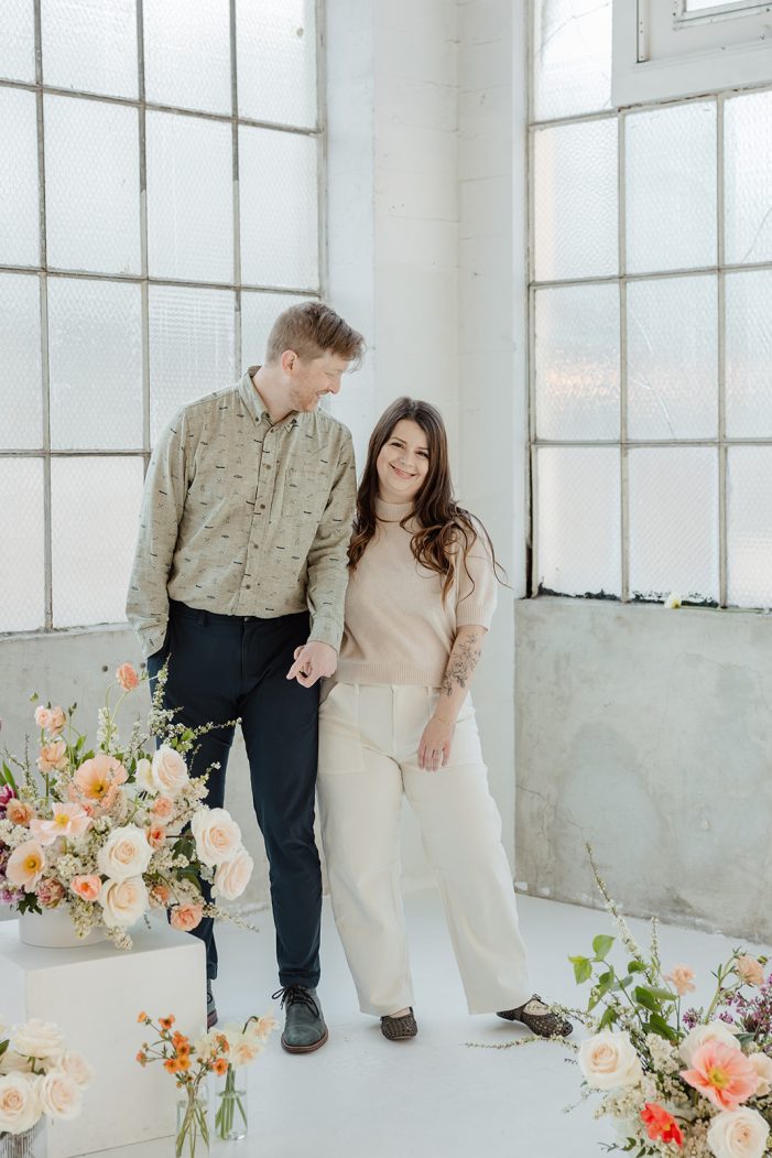 man and woman pose in studio with flowers