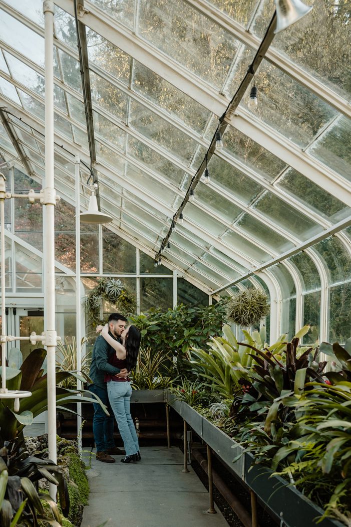 man and woman kiss in greenhouse