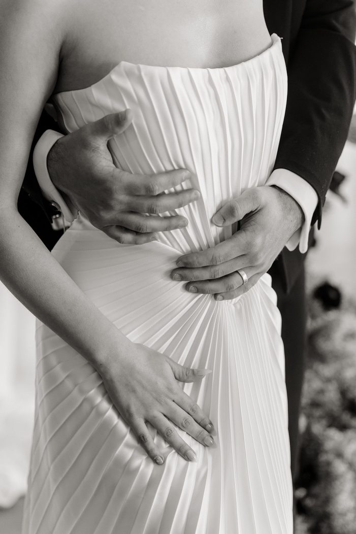 bride and groom are entangled in front of white backdrop