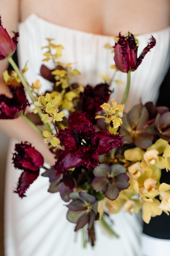 bride and groom are entangled in front of white backdrop