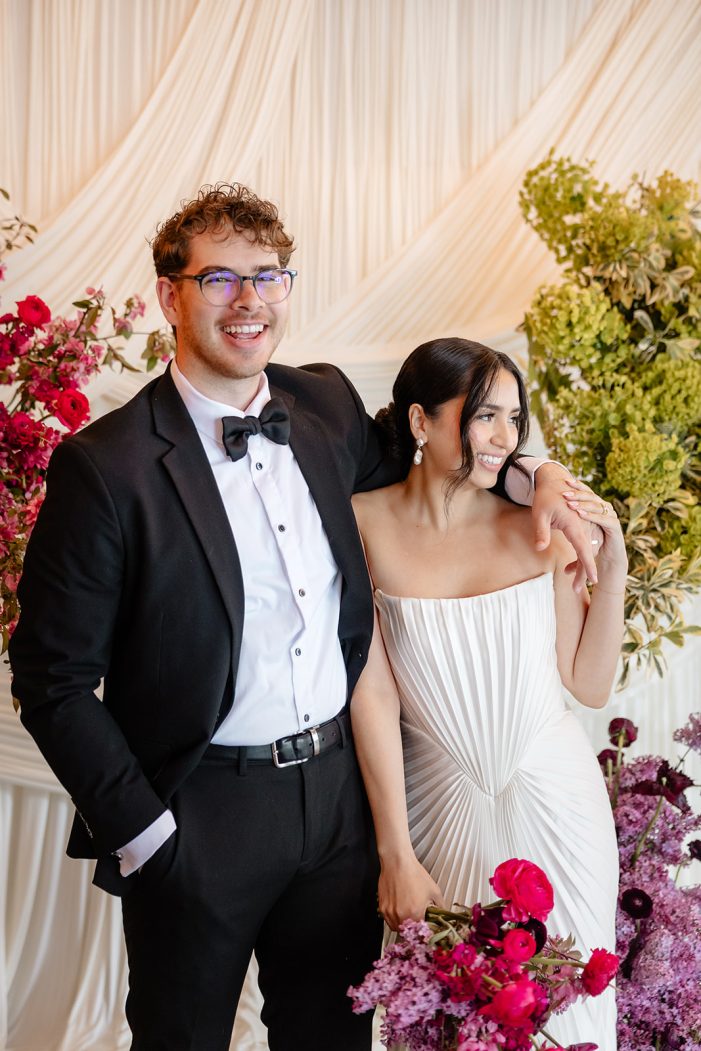 bride and groom are entangled in front of white backdrop
