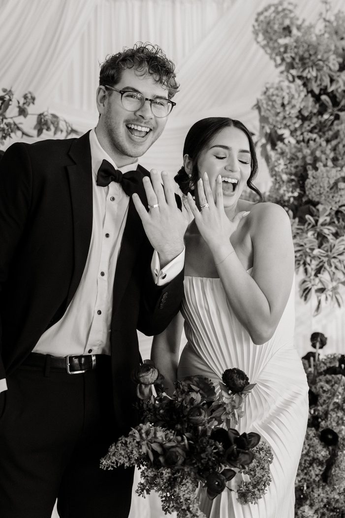 bride and groom are entangled in front of white backdrop