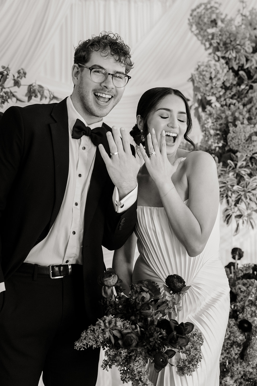 bride and groom are entangled in front of white backdrop