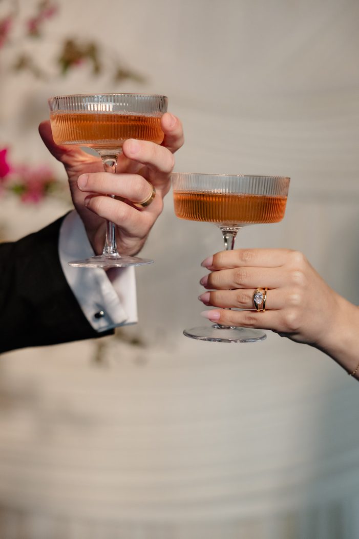 bride and groom toast in front of backdrop