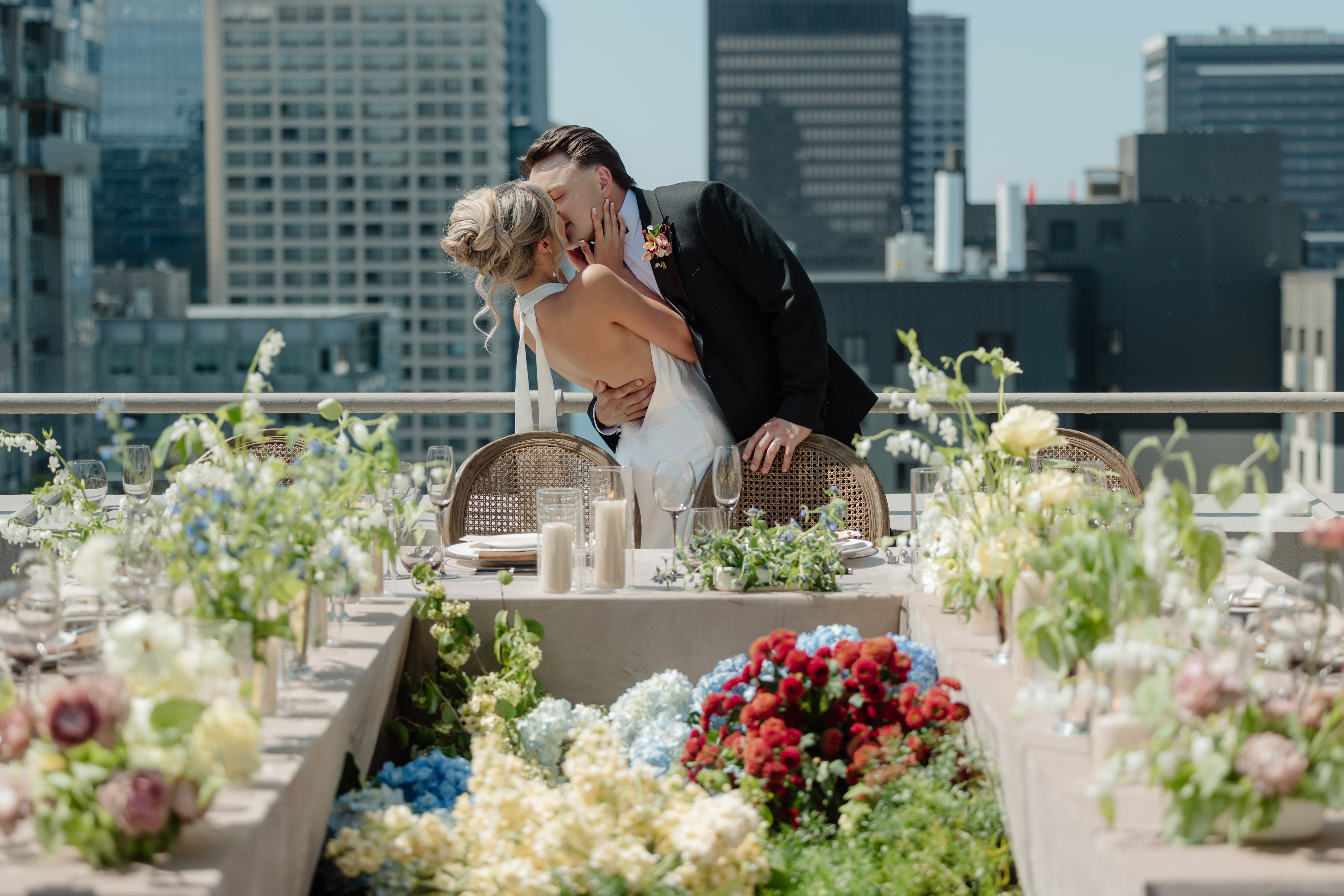 groom kisses bride at end of table