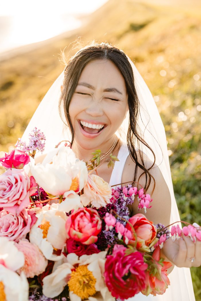 bride laughs while holding flowers